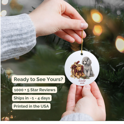 Hand holding a personalized Miniature Poodle (Gray) ceramic ornament beside a Christmas tree