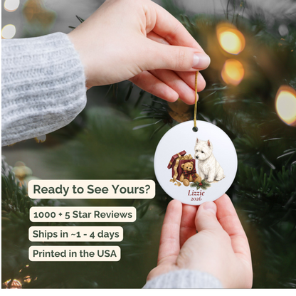 Hand holding a personalized West Highland Terrier ceramic ornament beside a Christmas tree