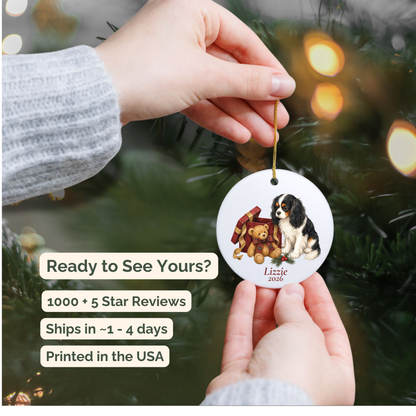 Hand holding a personalized Cavalier King Charles Spaniel (Tricolor) ceramic ornament beside a Christmas tree