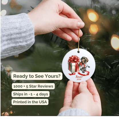 Hand holding a personalized German Shorthaired Pointer ceramic ornament beside a Christmas tree