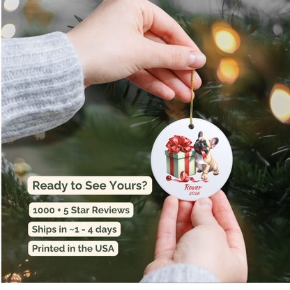 Hand holding a personalized fawn French Bulldog ceramic ornament beside a Christmas tree