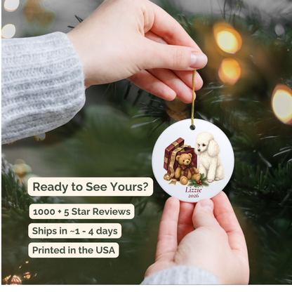 Hand holding a personalized Miniature Poodle ceramic ornament beside a Christmas tree
