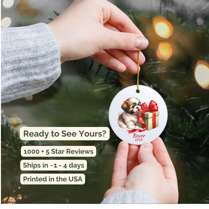 Hand holding a personalized Shih Tzu ceramic ornament beside a Christmas tree