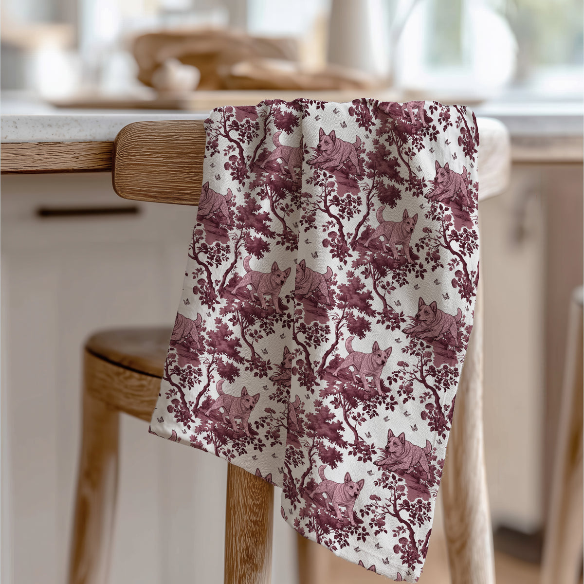Australian Cattle Dog Red Tea Towel with cranberry toile design, draped over a wooden chair in a kitchen.