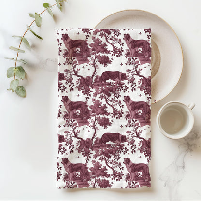 Border Collie Tea Towel with cranberry toile design, folded beside a plate and cup.