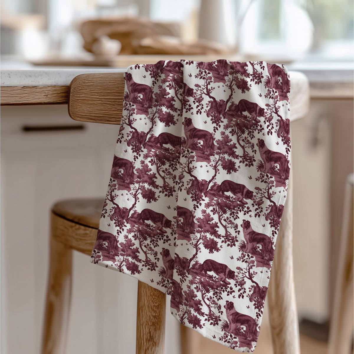 Border Collie Tea Towel with cranberry toile design, draped over a wooden chair in a kitchen.