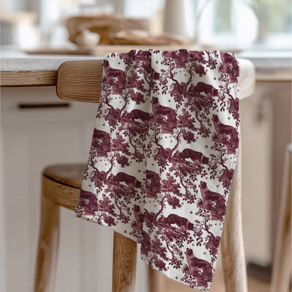 Border Collie Tea Towel with cranberry toile design, draped over a wooden chair in a kitchen.