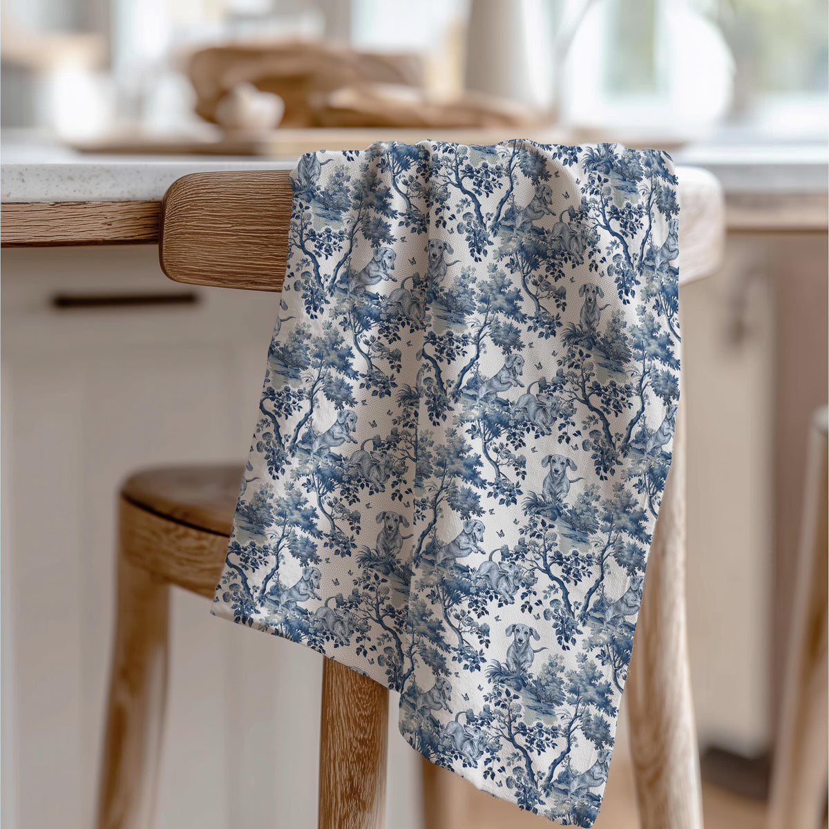 Dachshund Tea Towel with blue toile design, draped over a wooden chair in a kitchen.