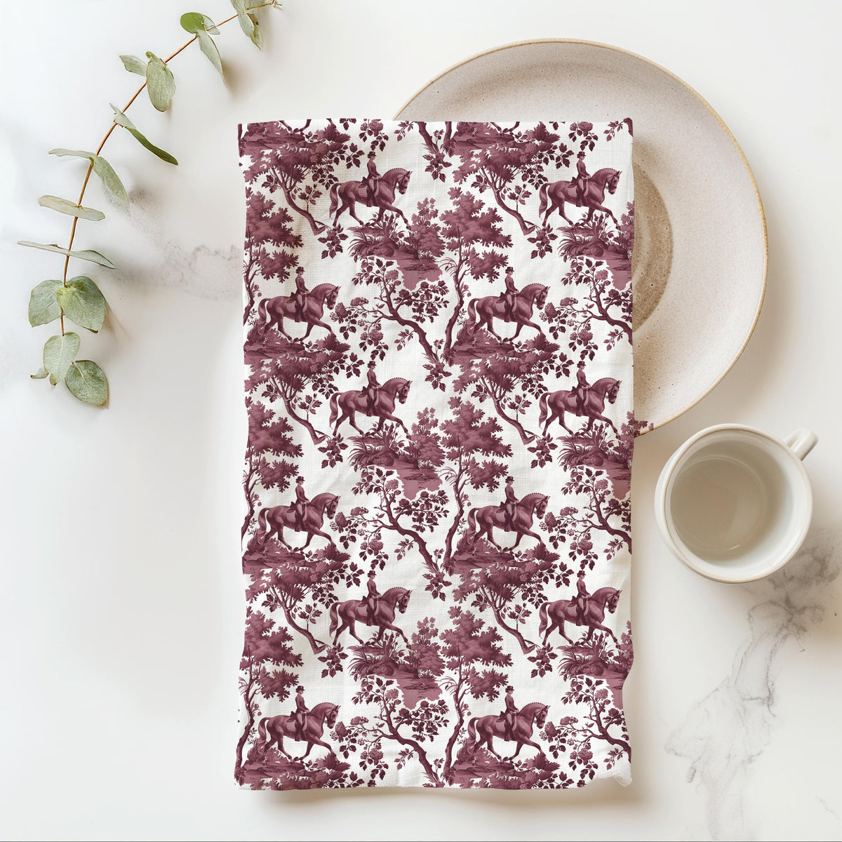 Dressage Horse Tea Towel with cranberry toile design, folded beside a plate and cup.