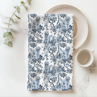 Goldendoodle Tea Towel with blue toile design, folded beside a plate and cup.