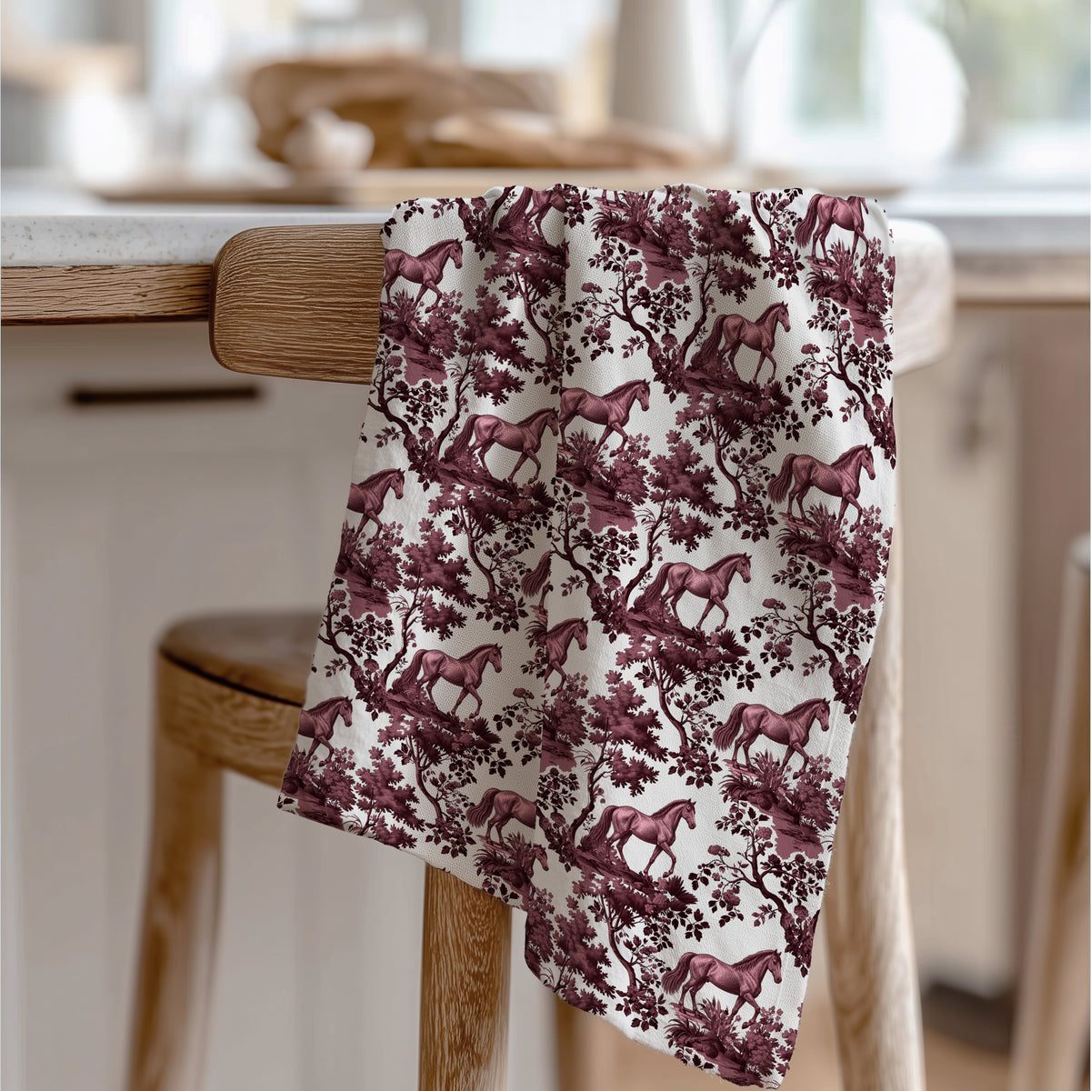 Horse Tea Towel with cranberry toile design, draped over a wooden chair in a kitchen.