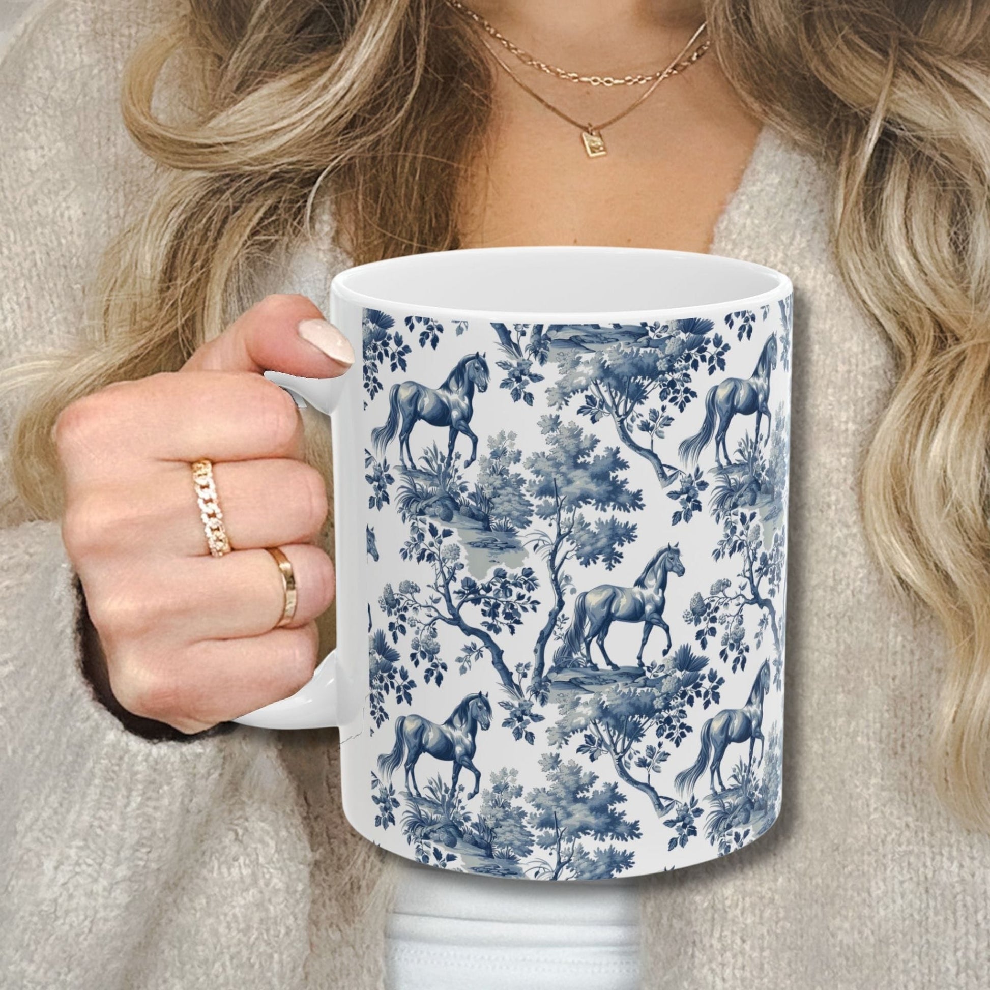 Classic blue toile Horse coffee cup against a cozy beige sweater