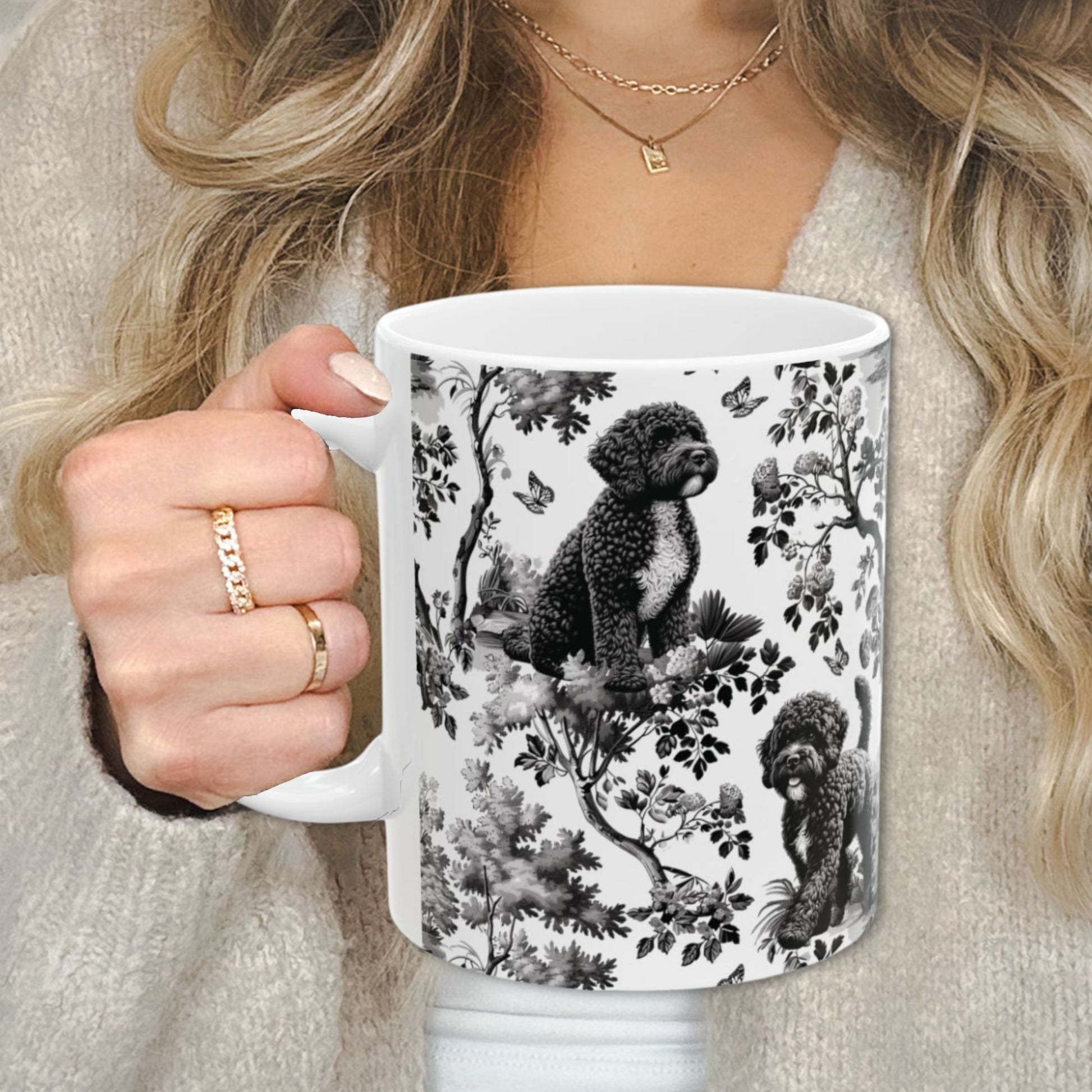 Black toile Portuguese Water Dog coffee cup against a cozy beige sweater