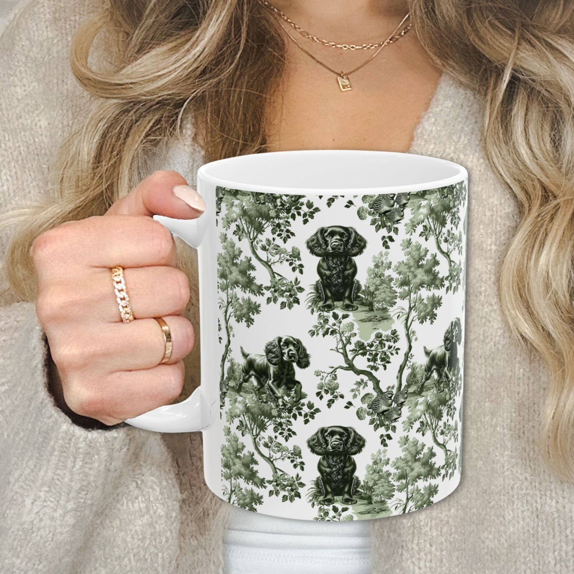 Sage green toile Boykin Spaniel coffee cup against a cozy beige sweater