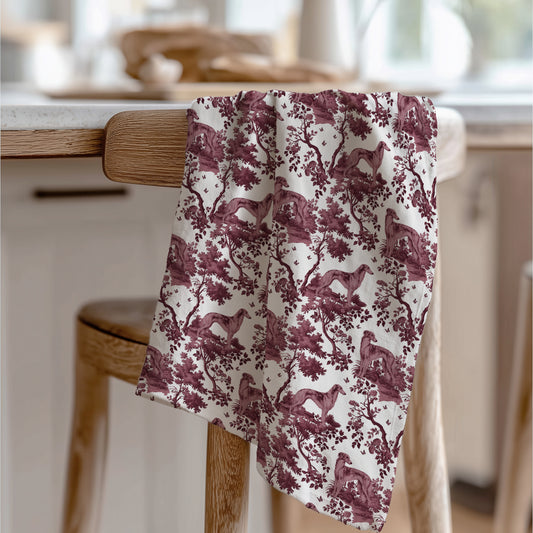 Silken Windhound Tea Towel with cranberry toile design, draped over a wooden chair in a kitchen.