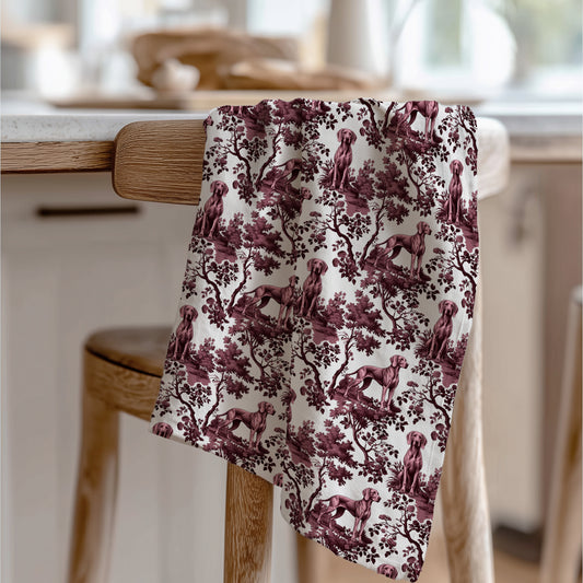 Weimaraner Tea Towel with cranberry toile design, draped over a wooden chair in a kitchen.
