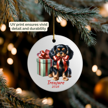 Hand holding a personalized Black and Tan Cavalier King Charles Spaniel ceramic ornament beside a Christmas tree