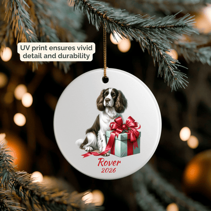 Hand holding a personalized English Springer Spaniel ceramic ornament beside a Christmas tree