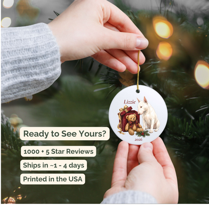 Hand holding a personalized Bull Terrier ceramic ornament beside a Christmas tree