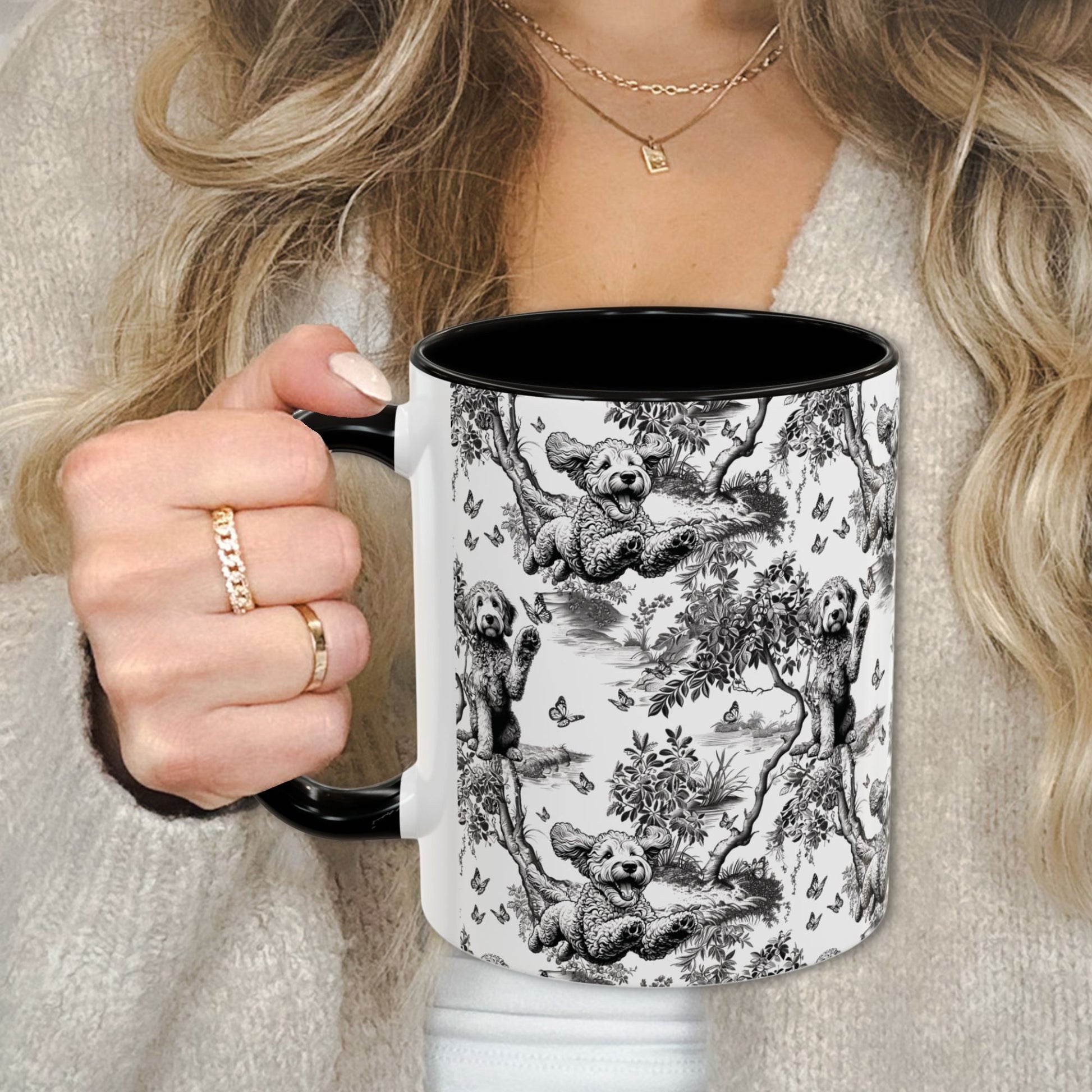Black toile Goldendoodle coffee cup against a cozy beige sweater